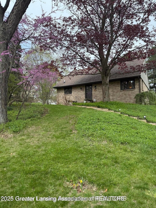 4794 Ardmore Ave, Okemos, MI 48864 - view of front of home featuring a front yard, brick siding, and roof with shingles