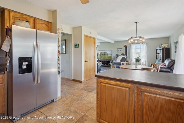 12898 Walker Rd, Leslie, MI 49251 - kitchen with stainless steel fridge, open floor plan, brown cabinets, baseboards, and pendant lighting