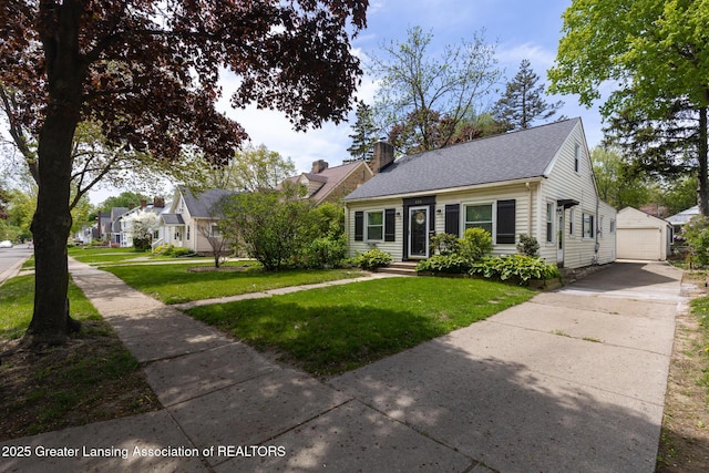 635 Division St, East Lansing, MI 48823 - view of front of house featuring an outbuilding, a detached garage, a front yard, driveway, and a chimney