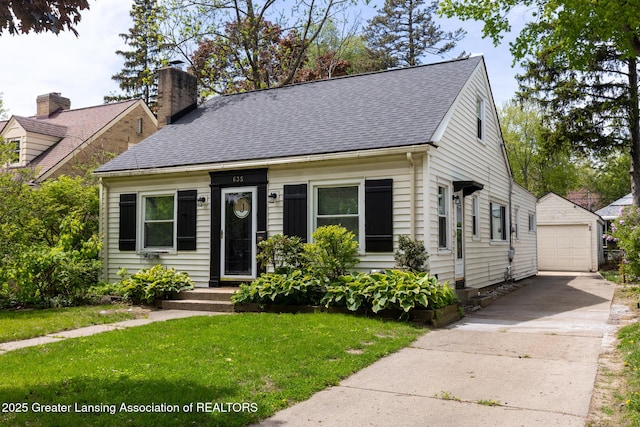 635 Division St, East Lansing, MI 48823 - cape cod house featuring a detached garage, an outdoor structure, a front lawn, roof with shingles, and concrete driveway