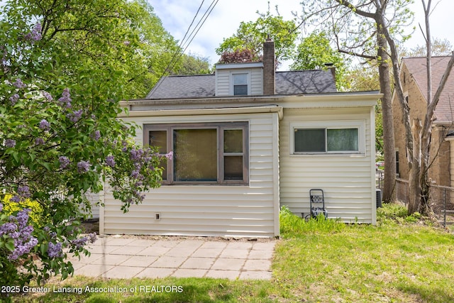 635 Division St, East Lansing, MI 48823 - view of front of property featuring a chimney, a patio area, a front lawn, and roof with shingles