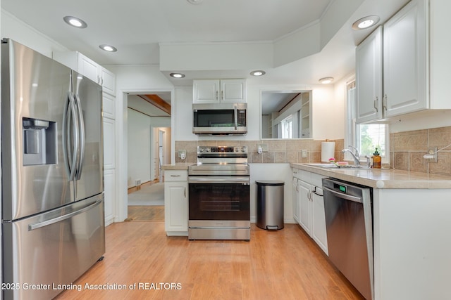 635 Division St, East Lansing, MI 48823 - kitchen featuring stainless steel appliances, a sink, light countertops, white cabinets, and light wood-style floors
