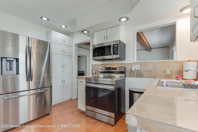 635 Division St, East Lansing, MI 48823 - kitchen with stainless steel appliances, light countertops, white cabinetry, a sink, and tasteful backsplash
