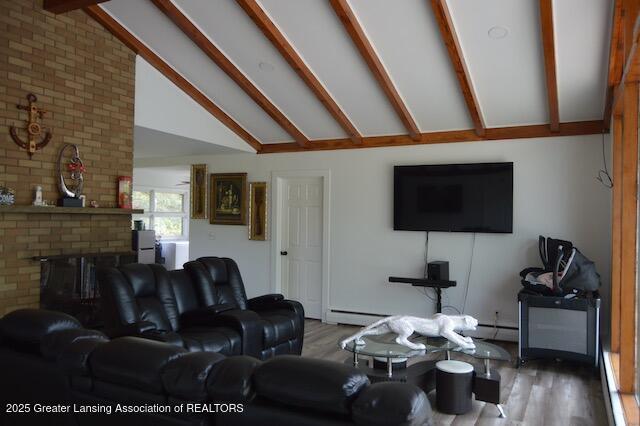 6157 W Stoll Rd, Lansing, MI 48906 - living area featuring wood finished floors, beam ceiling, high vaulted ceiling, a baseboard radiator, and a brick fireplace