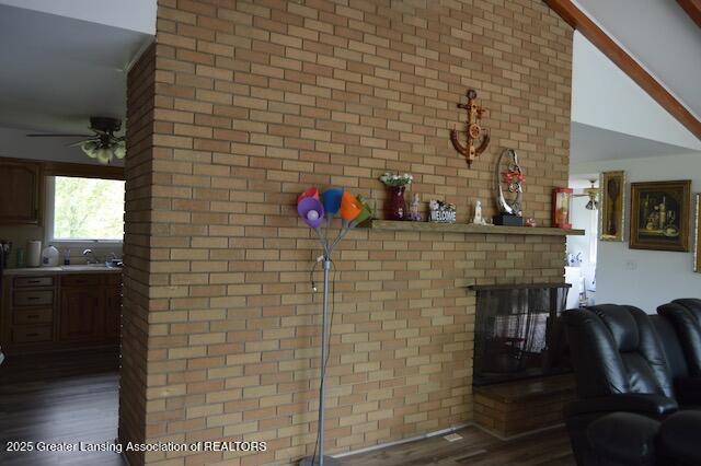 6157 W Stoll Rd, Lansing, MI 48906 - detailed view of ceiling fan, wood finished floors, a brick fireplace, and brick wall