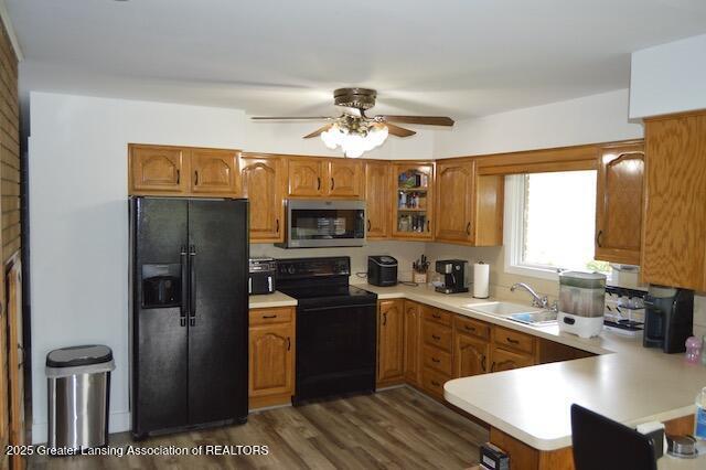 6157 W Stoll Rd, Lansing, MI 48906 - kitchen with black appliances, a sink, brown cabinets, a ceiling fan, and light countertops