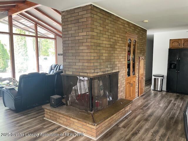 6157 W Stoll Rd, Lansing, MI 48906 - living room featuring dark wood-style floors, a fireplace, and brick wall