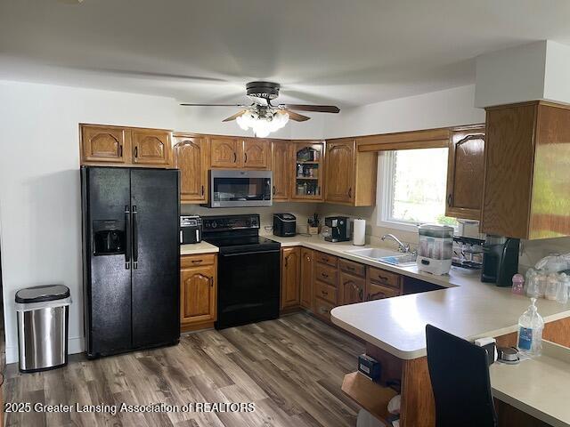 6157 W Stoll Rd, Lansing, MI 48906 - kitchen with black appliances, brown cabinetry, and light countertops