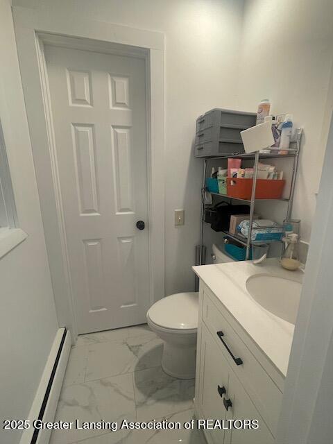 6157 W Stoll Rd, Lansing, MI 48906 - half bathroom featuring baseboard heating, marble finish floors, vanity, and toilet
