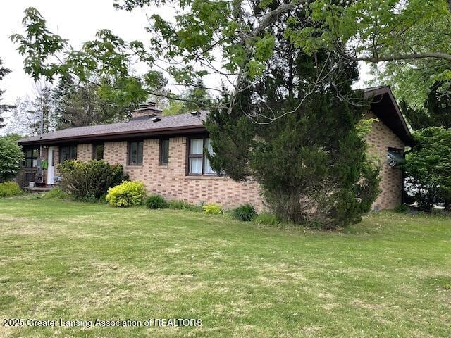 6157 W Stoll Rd, Lansing, MI 48906 - view of side of property with brick siding, a yard, and a chimney