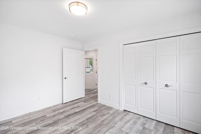 2107 Reo Rd, Lansing, MI 48910 - unfurnished bedroom with light wood finished floors, a closet, and baseboards