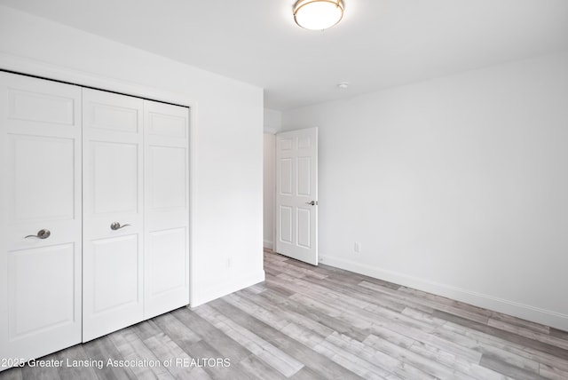 2107 Reo Rd, Lansing, MI 48910 - unfurnished bedroom featuring light wood finished floors, a closet, and baseboards