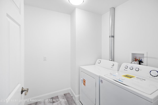 2107 Reo Rd, Lansing, MI 48910 - laundry room featuring washer and clothes dryer, light wood-type flooring, and baseboards