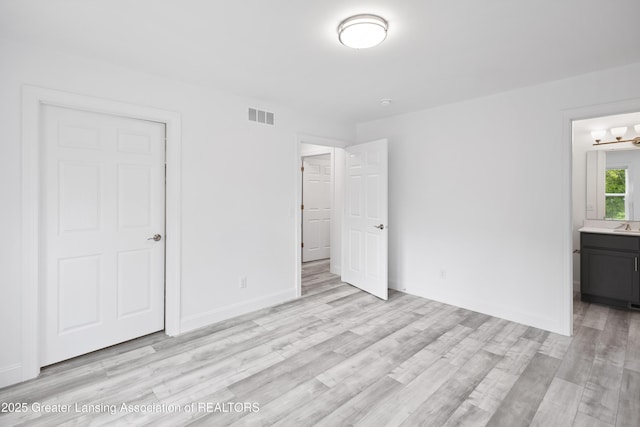 2107 Reo Rd, Lansing, MI 48910 - unfurnished bedroom featuring light wood-style flooring, baseboards, and connected bathroom