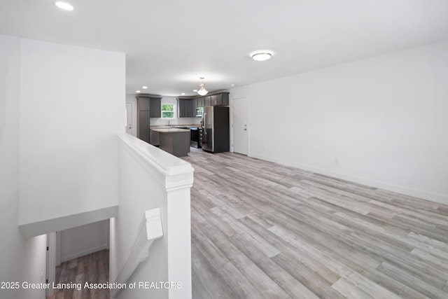 2107 Reo Rd, Lansing, MI 48910 - unfurnished living room featuring recessed lighting, light wood-style flooring, baseboards, and a sink