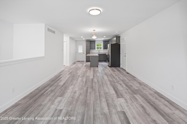 2107 Reo Rd, Lansing, MI 48910 - unfurnished living room with light wood-style flooring, baseboards, and recessed lighting