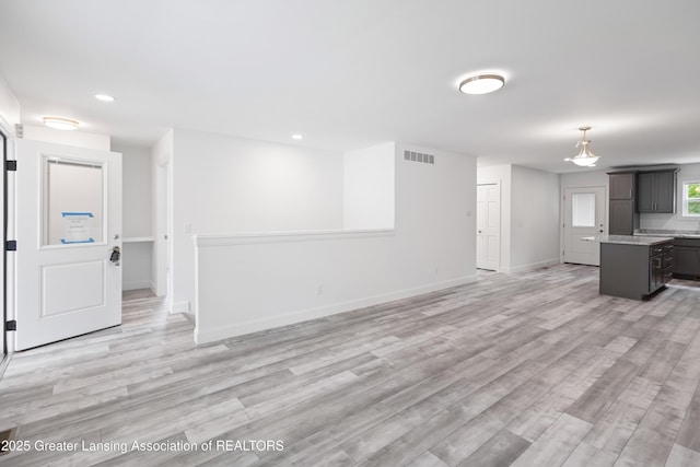 2107 Reo Rd, Lansing, MI 48910 - unfurnished living room featuring baseboards, light wood-type flooring, and recessed lighting