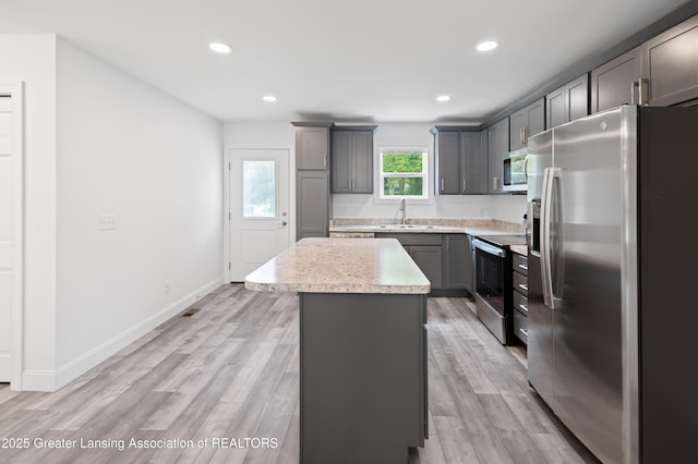 2107 Reo Rd, Lansing, MI 48910 - kitchen with appliances with stainless steel finishes, a center island, a sink, light countertops, and gray cabinetry