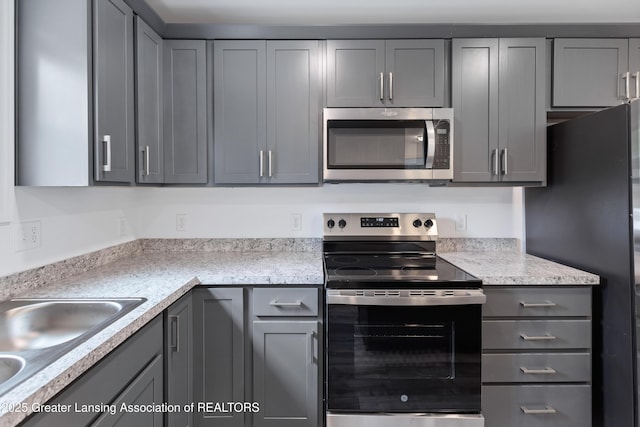 2107 Reo Rd, Lansing, MI 48910 - kitchen featuring appliances with stainless steel finishes, gray cabinetry, and a sink