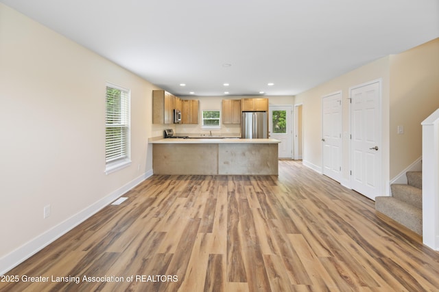 4205 Glenburne Blvd, Lansing, MI 48911 - kitchen featuring appliances with stainless steel finishes, a peninsula, light wood-style flooring, baseboards, and light countertops