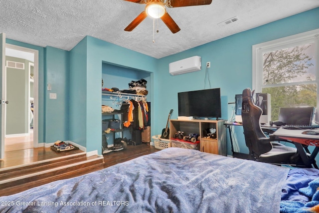 513 E Grand River Rd, Laingsburg, MI 48848 - bedroom with a wall unit AC, wood finished floors, a textured ceiling, a closet, and ceiling fan