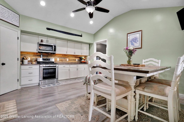 513 E Grand River Rd, Laingsburg, MI 48848 - kitchen with stainless steel appliances, lofted ceiling, backsplash, ceiling fan, and light wood-style flooring