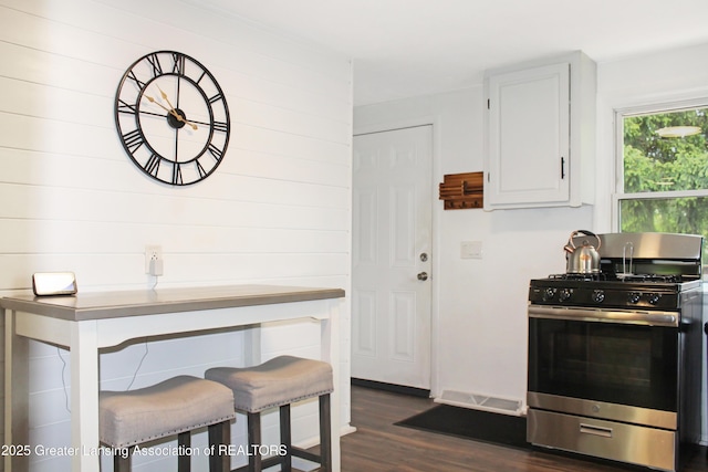 14275 Webster Rd, Bath, MI 48808 - kitchen featuring stainless steel gas range oven, dark wood-type flooring, white cabinets, and wood walls