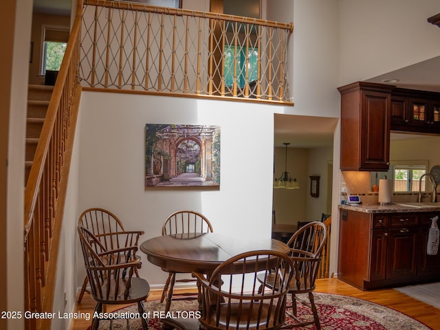 1561 Roseland Ave, East Lansing, MI 48823 - dining room with light wood-style flooring, a high ceiling, and stairs