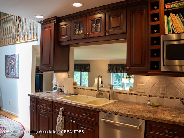 1561 Roseland Ave, East Lansing, MI 48823 - kitchen with stainless steel appliances, a sink, backsplash, glass insert cabinets, and baseboards