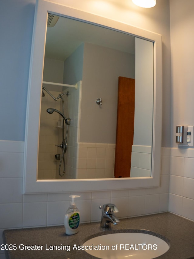 1561 Roseland Ave, East Lansing, MI 48823 - bathroom featuring tile walls, vanity, tiled shower, and a wainscoted wall