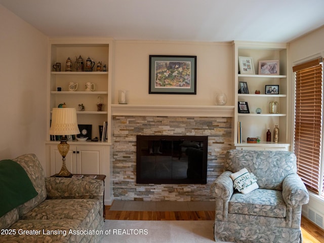 1561 Roseland Ave, East Lansing, MI 48823 - living area featuring built in features, wood finished floors, and a stone fireplace