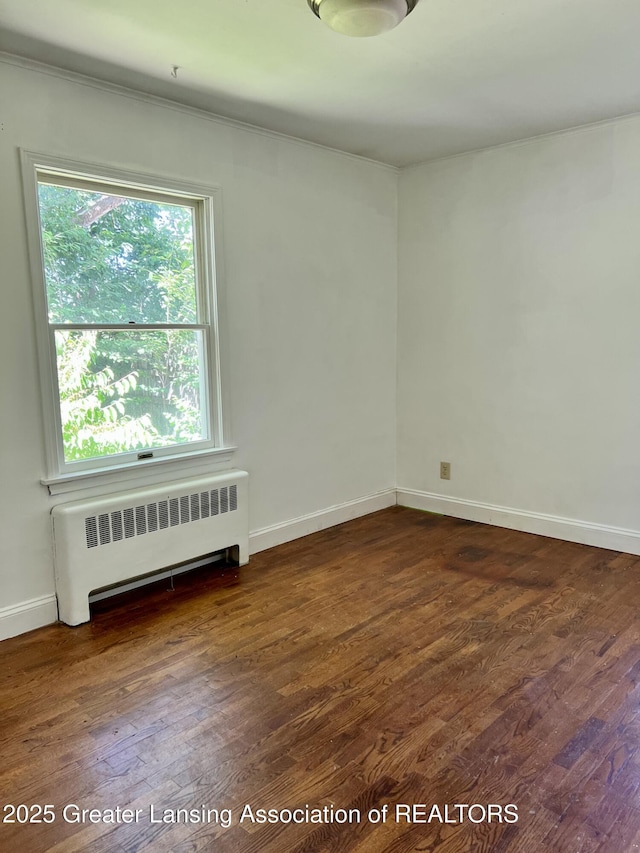 341 W Saginaw St, East Lansing, MI 48823 - spare room with radiator, dark wood-style flooring, baseboards, and ornamental molding