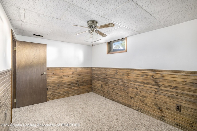 7319 E 5th Point Highway, Eaton Rapids, MI 48827 - carpeted empty room with wood walls, wainscoting, a paneled ceiling, and a ceiling fan