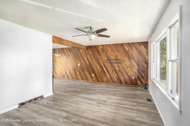 7319 E 5th Point Highway, Eaton Rapids, MI 48827 - unfurnished room featuring wooden walls, baseboards, a ceiling fan, a textured ceiling, and wood finished floors
