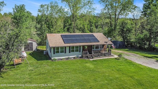 7319 E 5th Point Highway, Eaton Rapids, MI 48827 - view of front of property with solar panels, a shingled roof, a storage shed, a front lawn, and an outbuilding