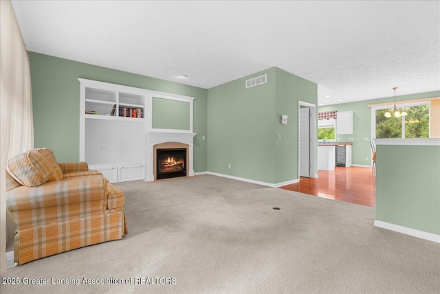 3816 Kiskadee Dr, East Lansing, MI 48823 - unfurnished living room with carpet flooring, a fireplace with flush hearth, a chandelier, and baseboards