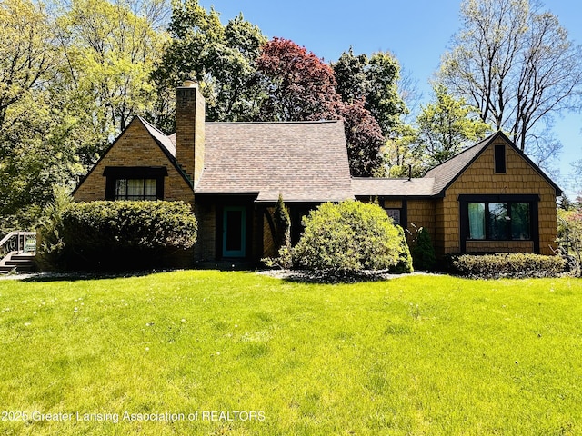 812 Dryer Farm Rd, Lansing, MI 48917 - tudor house featuring a front lawn, a chimney, and a shingled roof