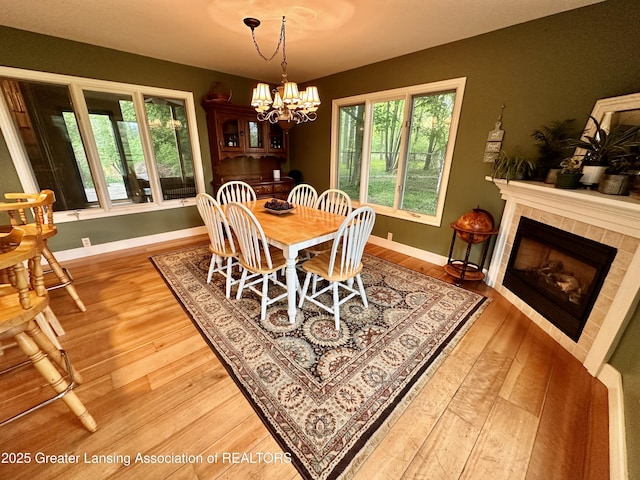 812 Dryer Farm Rd, Lansing, MI 48917 - dining space featuring wood finished floors, a chandelier, baseboards, and a tile fireplace