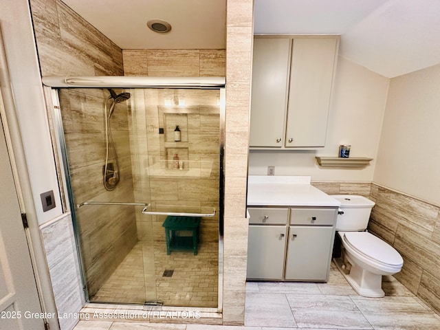 812 Dryer Farm Rd, Lansing, MI 48917 - bathroom with a shower stall, toilet, vanity, wainscoting, and tile walls
