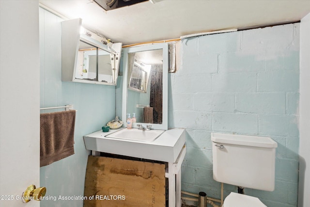 912 Pacific Ave, Lansing, MI 48910 - bathroom featuring toilet, concrete block wall, and vanity