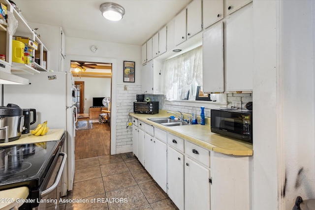 912 Pacific Ave, Lansing, MI 48910 - kitchen featuring black microwave, a sink, a ceiling fan, tasteful backsplash, and light countertops