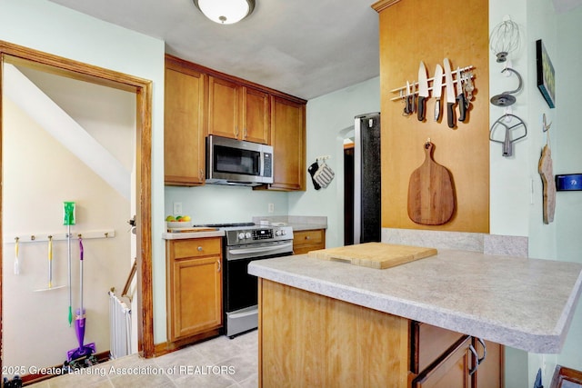 1411 Poxson Ave, Lansing, MI 48910 - kitchen featuring stainless steel appliances, light countertops, brown cabinetry, and light tile patterned floors