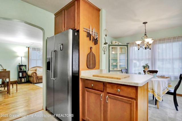 1411 Poxson Ave, Lansing, MI 48910 - kitchen with stainless steel fridge, brown cabinets, a chandelier, light countertops, and hanging light fixtures