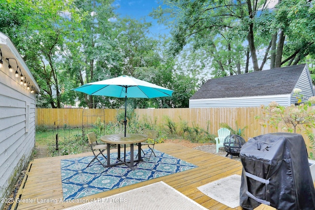 1411 Poxson Ave, Lansing, MI 48910 - wooden terrace featuring a fenced backyard, area for grilling, and a fire pit