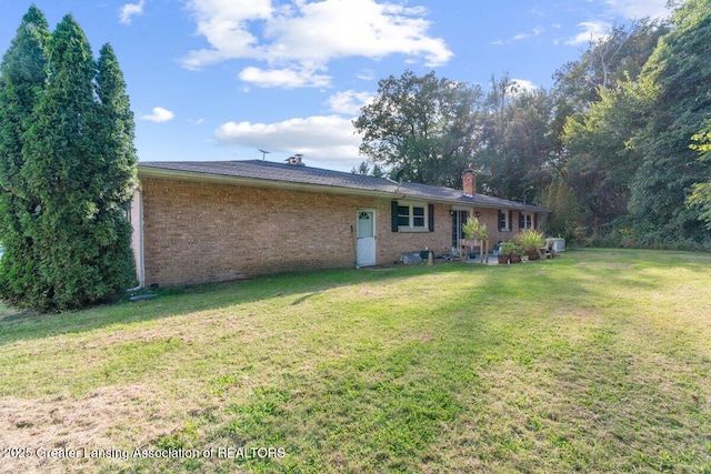 15988 Comdon Rd, Albion, MI 49224 - rear view of property with brick siding, a yard, and a chimney