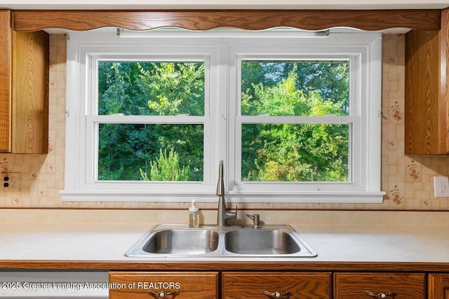 15988 Comdon Rd, Albion, MI 49224 - kitchen featuring a sink, light countertops, backsplash, and brown cabinetry