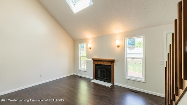 4918 Westhaven Blvd, Lansing, MI 48917 - unfurnished living room with lofted ceiling, plenty of natural light, a fireplace with flush hearth, dark wood-type flooring, and baseboards