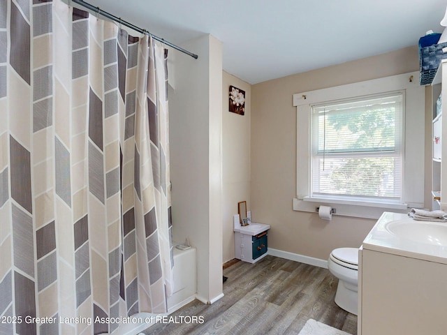 1023 Bement St, Lansing, MI 48912 - bathroom with wood finished floors, toilet, vanity, baseboards, and shower / bath combination with curtain