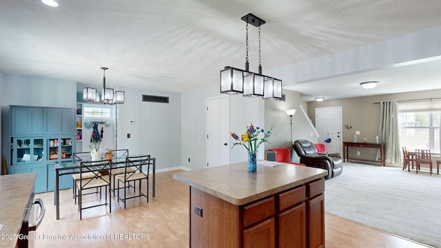 1055 Oakwood Dr, Dewitt, MI 48820 - kitchen with a chandelier, open floor plan, brown cabinetry, light wood-style flooring, and a kitchen island