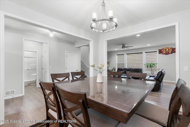 5651 Copper Creek Dr, Haslett, MI 48840 - dining room with light wood-style floors, stairs, a chandelier, ceiling fan, and baseboards